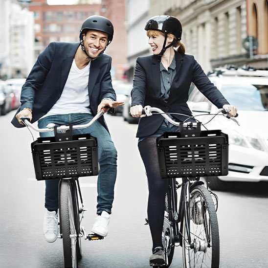 deux cyclistes homme et femme souriants habiller en veston sur chacun un velo transportant panier avant pour velo vide noir en plastique