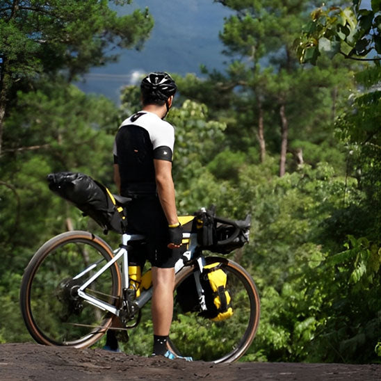 Cycliste debout avec multiples sacoche velo admirant vue foret
