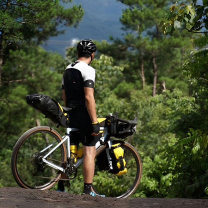 Cycliste debout avec multiples sacoche velo admirant vue foret