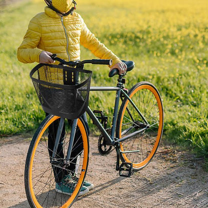 Cycliste habille de jaune debout pres velo dans champ ensoleille avec panier pour velo femme