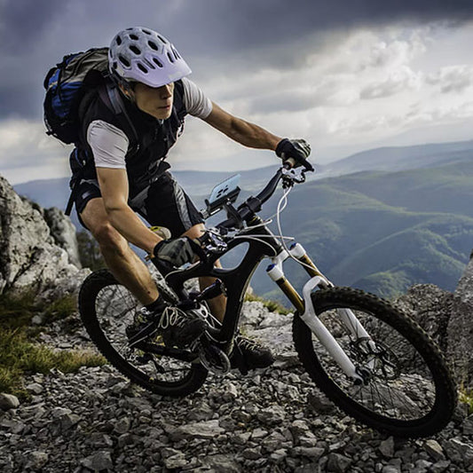 cycliste_avec_casque_et_sac_a_dos_sur_velo_tout_terrain_en_montagne_rocheu
