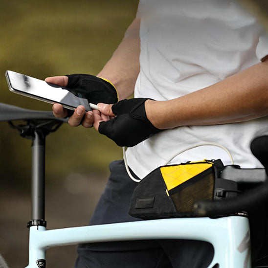 cycliste_debout_tenant_telephone_devant_velo_avec_sac_velo_contenant_chargeur_telephon