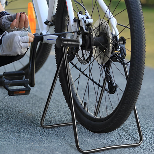 cycliste_qui_fait_entretien_de_velo_sur_support_rack_a_velo_exterieur_sur_pave_asphalt