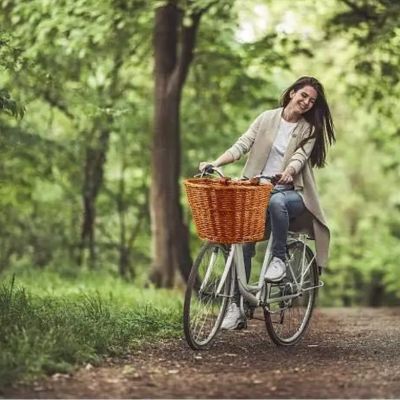 femme a bicyclette avec panier conventionnel panier velo brun beige rotin