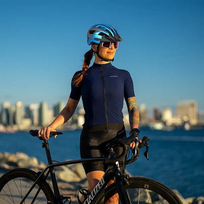 femme cycliste devant velo près de l'eau avec casque velo visiere