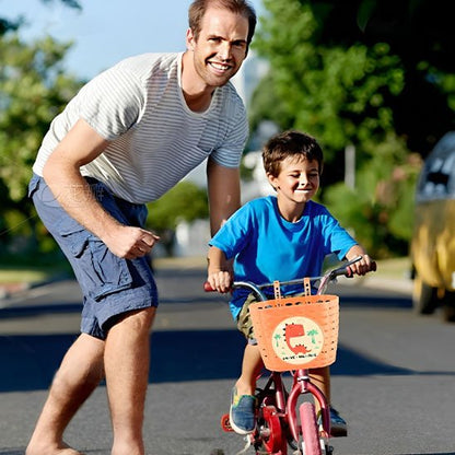 garcon a velo avec t-shirt bleu a velo rouge et petite roues avec velo panier orange autocollant dinausore assister par pere pour apprentissage