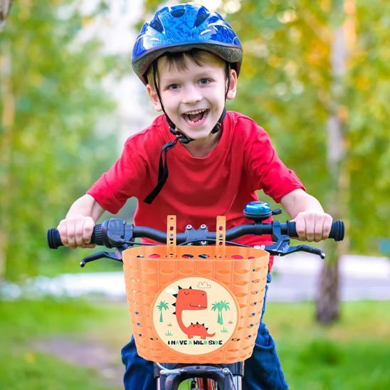 garcon souriant sur velo dans parc ensoleille avec casque bleu et velo panier orange autocollant dinausore