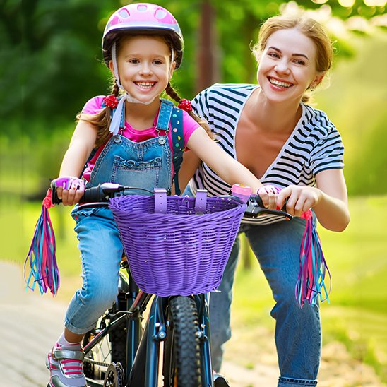 mere pres de fillette dans parc sur velo bleu avec ensemble panier a velo violet avec rubans decoratifs pour guidon et sonnette