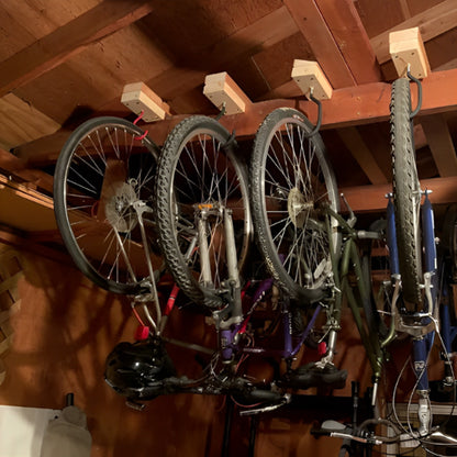 quatre velos suspendus par roues a l envers horizontalement par support velo mural dans grange au plafond