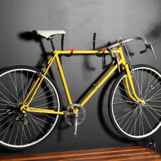 velo de course jaune devant mur gris suspendu par support mural pour velo