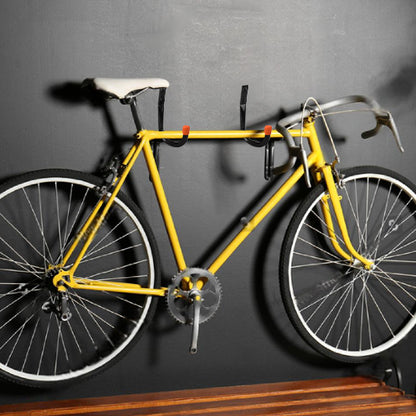velo de course jaune devant mur gris suspendu par support mural pour velo