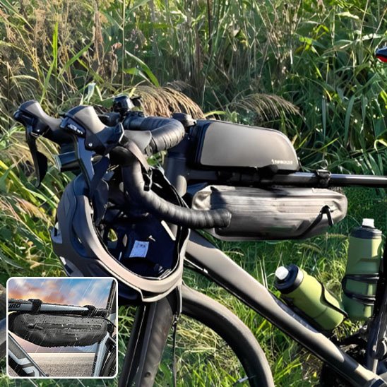 velo de course route noir devant hautes herbes avec deux gourdes et deux sacoches velo cadre sur cadre centrales du velo avec casque sur guidon